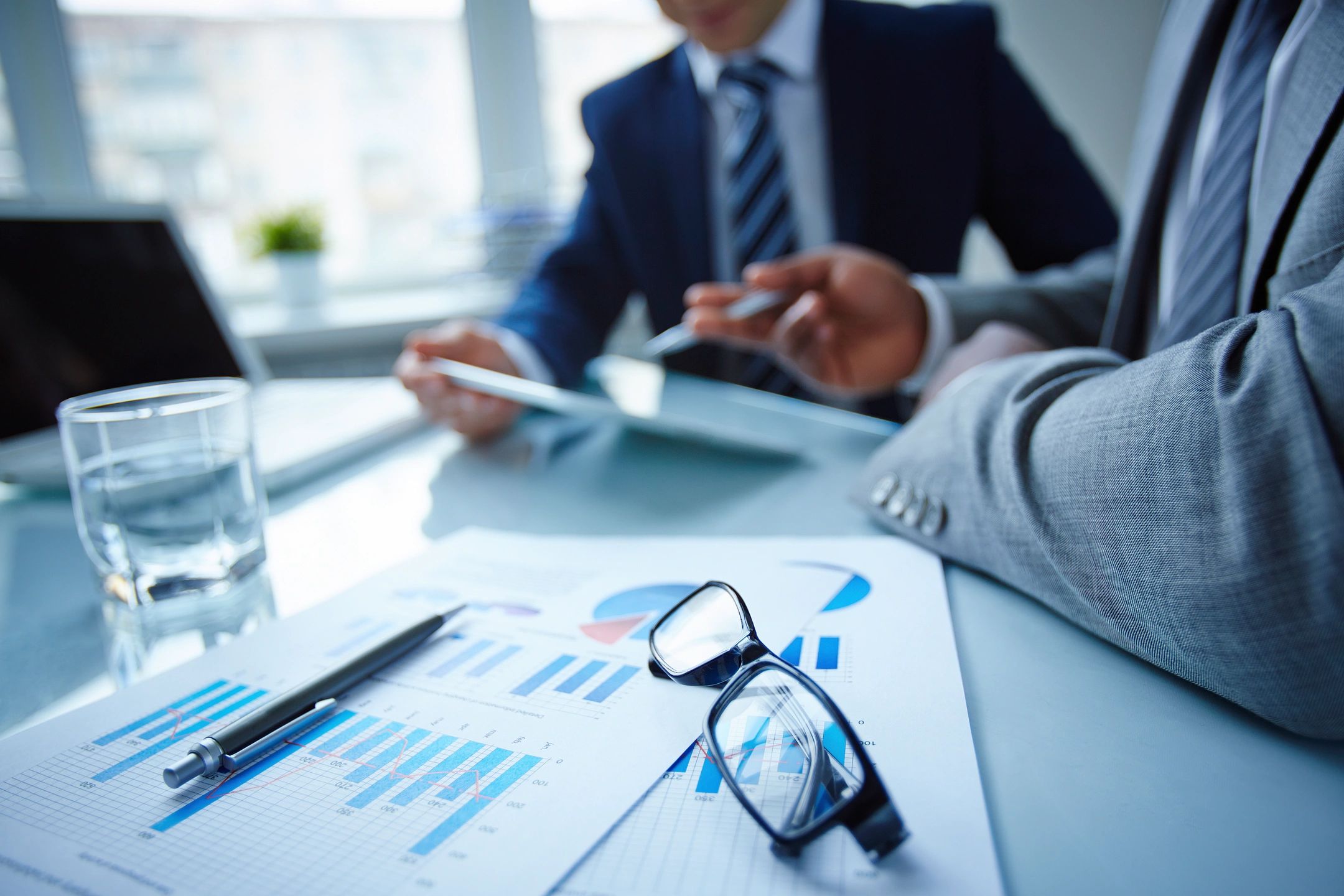 Two men sit at a table covered in business documents, a pen, and glasses. Get insurance in Bradenton.